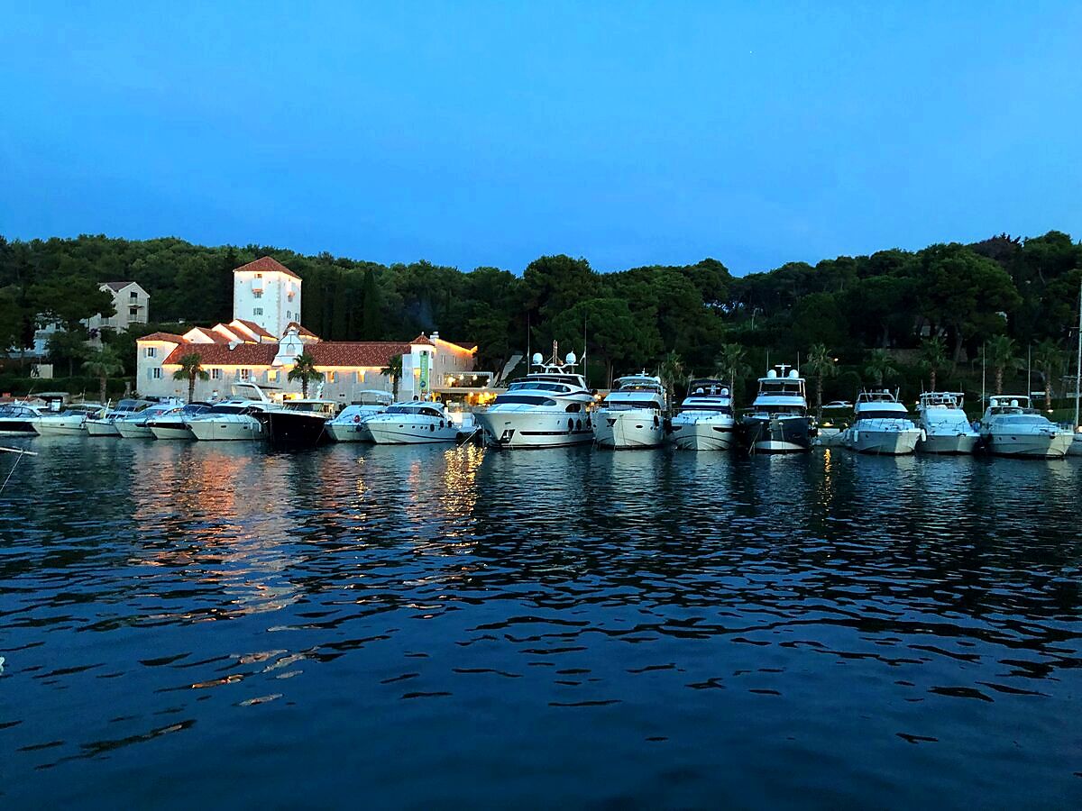 Marina at dusk with yachts and illuminated stone buildings on Šolta